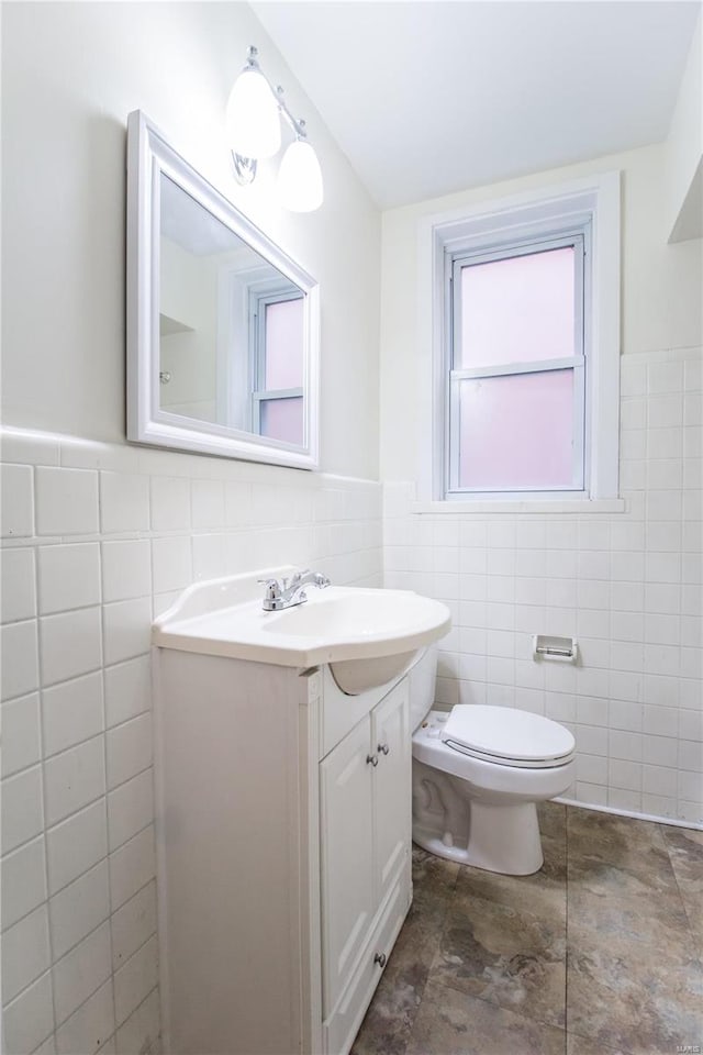 bathroom featuring vanity, toilet, and tile walls