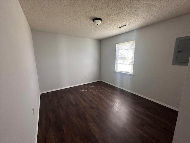 empty room with electric panel, a textured ceiling, and dark hardwood / wood-style flooring