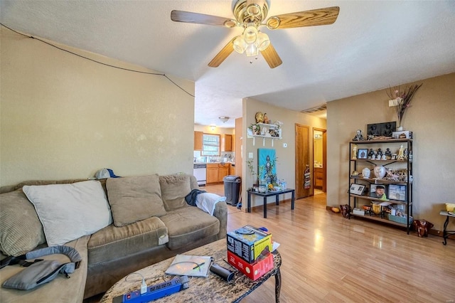 living room featuring light hardwood / wood-style flooring, a textured ceiling, and ceiling fan