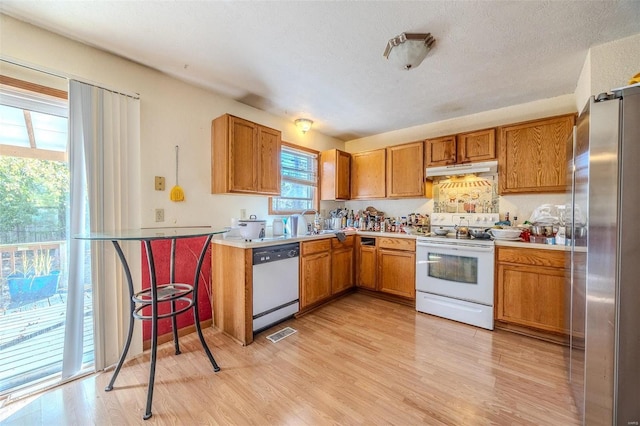 kitchen featuring white appliances, a textured ceiling, light hardwood / wood-style flooring, and sink