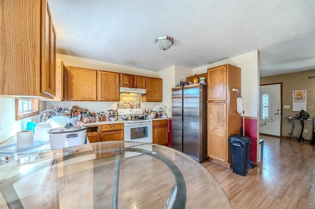 kitchen with stainless steel fridge, white electric range oven, light wood-type flooring, and a textured ceiling