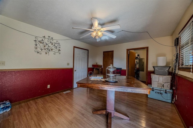 dining room with hardwood / wood-style floors, electric panel, a textured ceiling, and ceiling fan