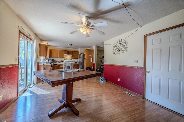 dining area featuring light hardwood / wood-style flooring, a textured ceiling, and ceiling fan