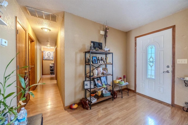 entryway with a textured ceiling and light hardwood / wood-style floors