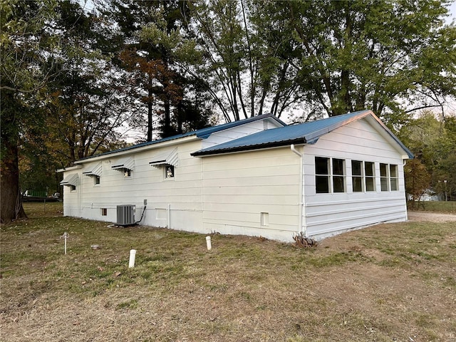 view of property exterior with a lawn and central AC unit