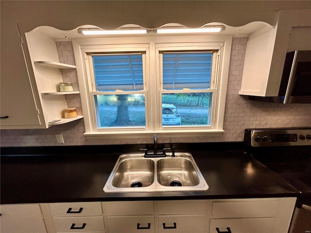 kitchen featuring black range with electric stovetop, sink, white cabinetry, and decorative backsplash