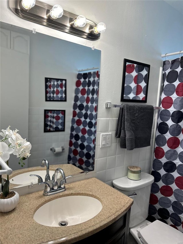 bathroom featuring toilet, vanity, and tile walls