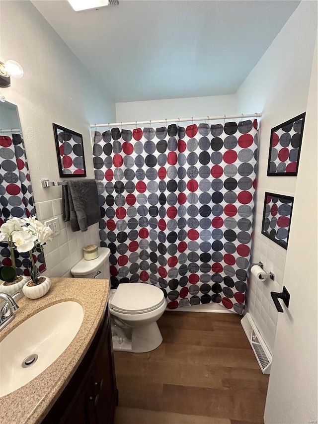 bathroom with hardwood / wood-style flooring, toilet, vanity, tile walls, and walk in shower