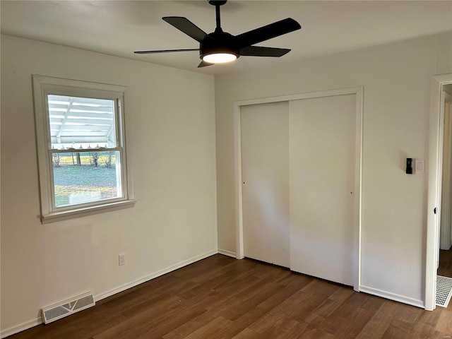 unfurnished bedroom with dark hardwood / wood-style flooring, a closet, and ceiling fan