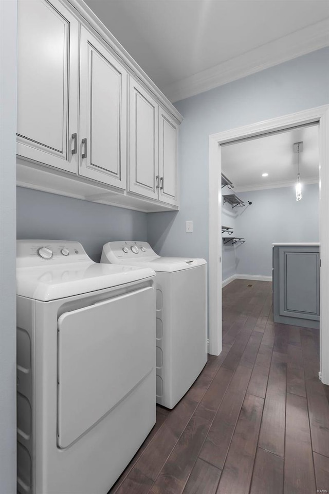 clothes washing area featuring dark wood-type flooring, ornamental molding, cabinets, and washing machine and clothes dryer