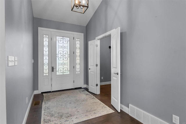 entrance foyer with dark wood-type flooring, lofted ceiling, and an inviting chandelier