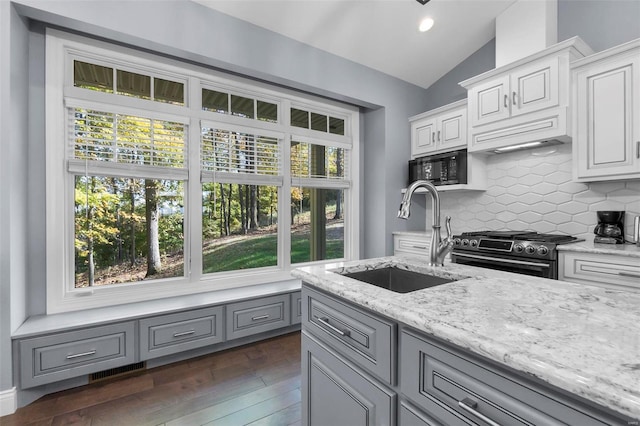 kitchen with dark hardwood / wood-style floors, stainless steel stove, sink, vaulted ceiling, and white cabinets