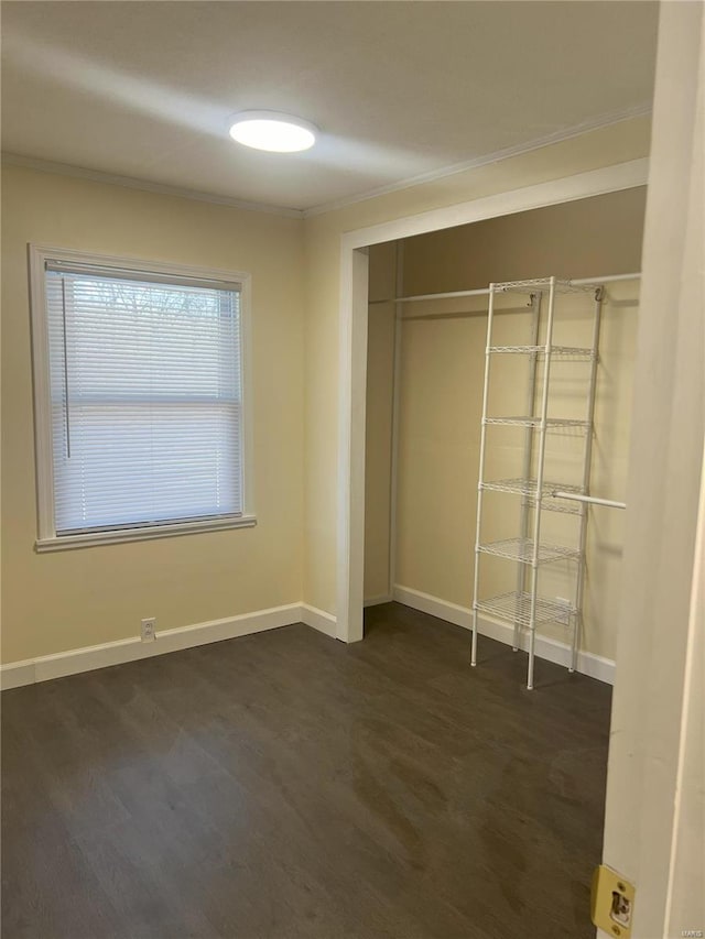 unfurnished bedroom featuring dark hardwood / wood-style flooring, ornamental molding, and a closet