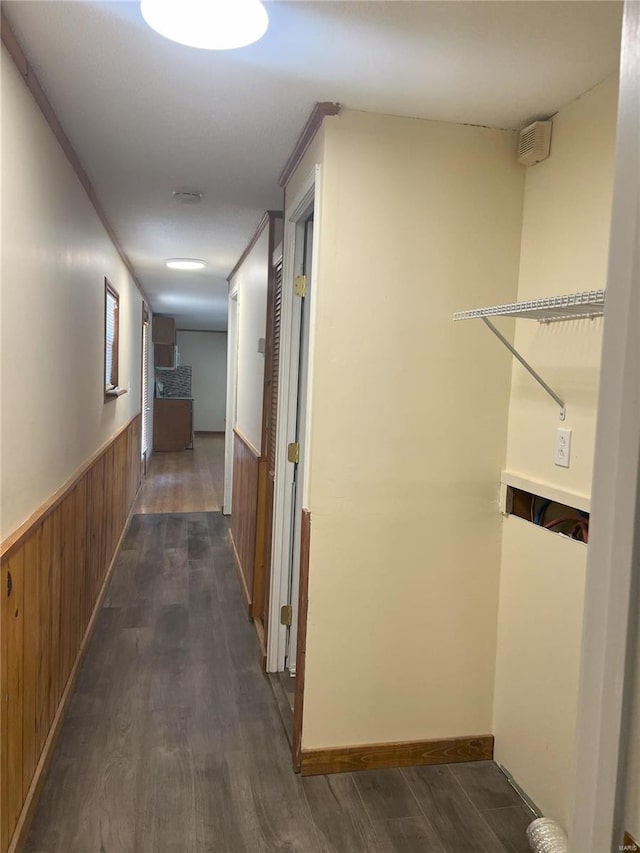 hall featuring wooden walls, dark wood-type flooring, and ornamental molding