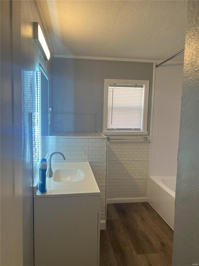 bathroom with wood-type flooring, vanity, tile walls, and a healthy amount of sunlight