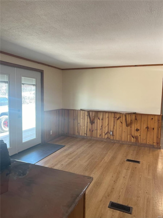 interior space with wooden walls, light hardwood / wood-style flooring, and a textured ceiling