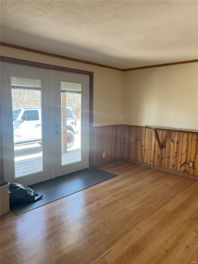 unfurnished room featuring wood walls, wood-type flooring, and a textured ceiling