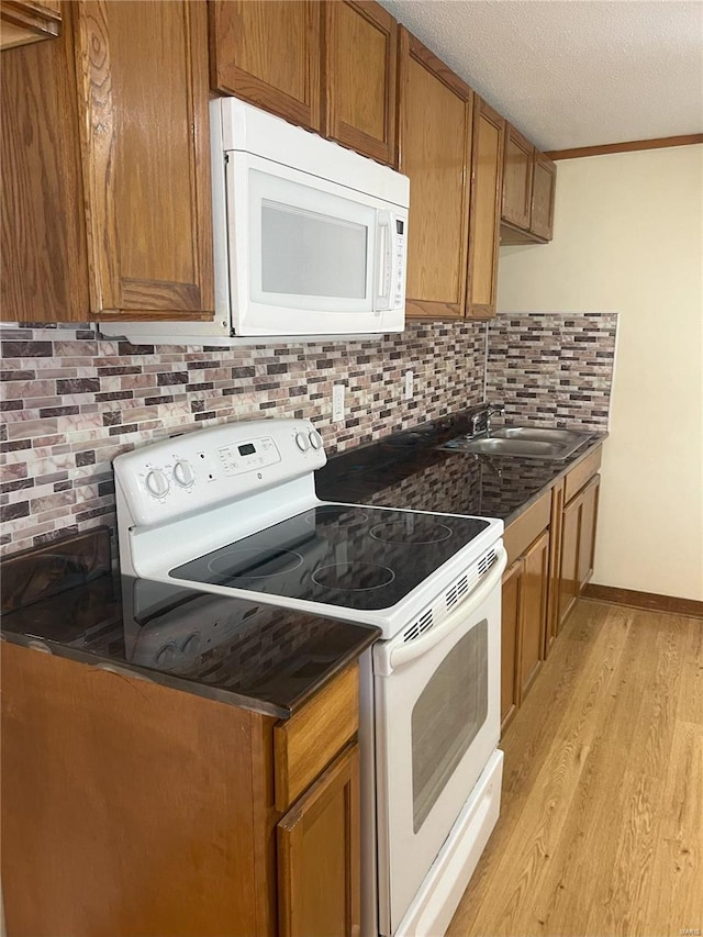 kitchen featuring light hardwood / wood-style floors, sink, white appliances, and backsplash