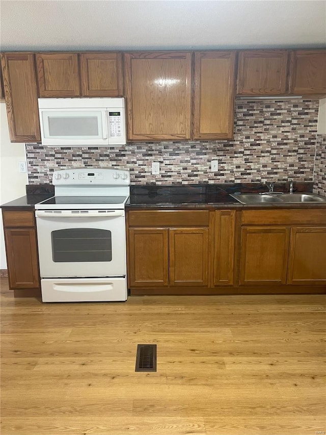 kitchen with light wood-type flooring, white appliances, sink, and tasteful backsplash