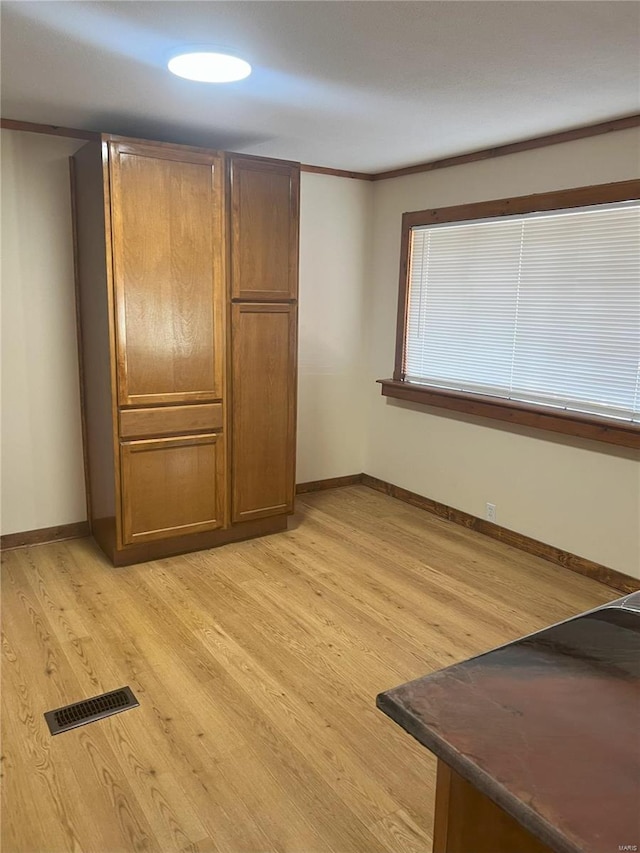 interior space featuring light wood-type flooring and crown molding