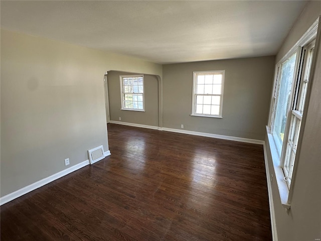 spare room with a wealth of natural light and dark hardwood / wood-style flooring