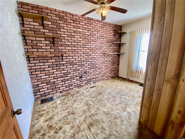 carpeted spare room featuring a textured ceiling, brick wall, and ceiling fan