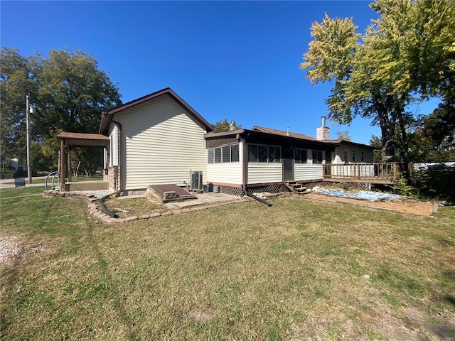 rear view of property featuring a wooden deck and a lawn