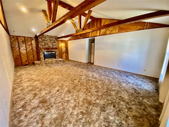 unfurnished living room featuring a stone fireplace, beamed ceiling, carpet floors, and wooden walls