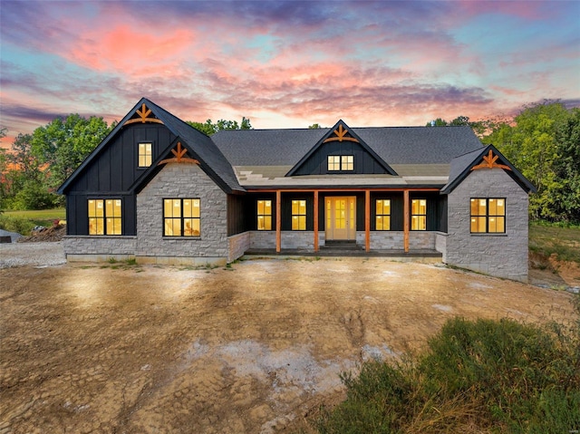 back house at dusk featuring a porch