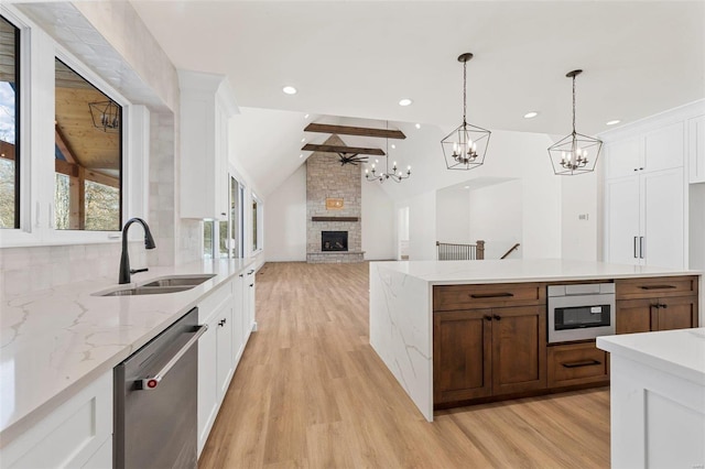 kitchen with dishwasher, white cabinets, a fireplace, vaulted ceiling with beams, and sink