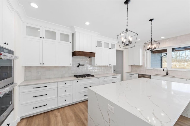 kitchen with sink, white cabinetry, a center island, light stone countertops, and appliances with stainless steel finishes