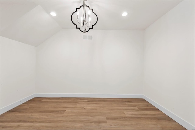 unfurnished dining area featuring light wood-type flooring, vaulted ceiling, and a chandelier