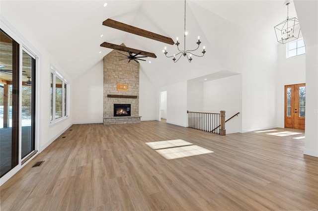 unfurnished living room with high vaulted ceiling, beam ceiling, light wood-type flooring, ceiling fan with notable chandelier, and a fireplace