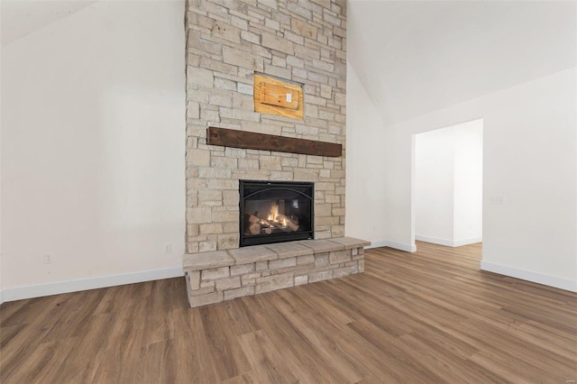 unfurnished living room with high vaulted ceiling, a fireplace, and hardwood / wood-style flooring