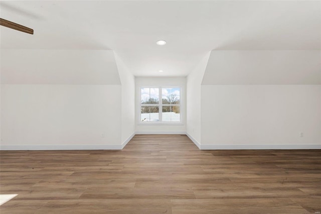 additional living space featuring vaulted ceiling and light hardwood / wood-style flooring