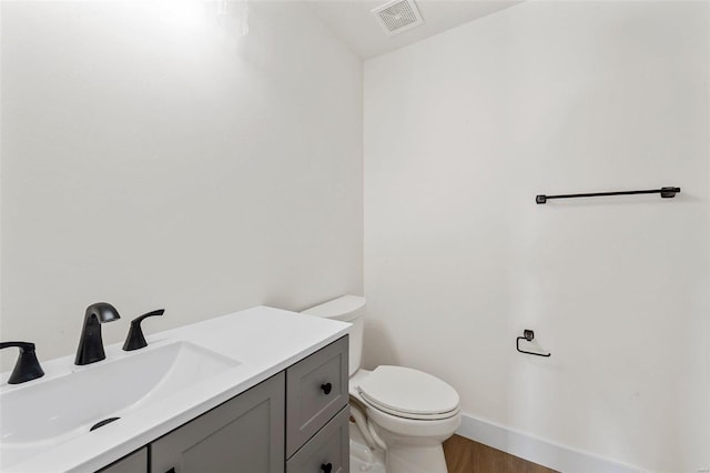 bathroom with toilet, vanity, and hardwood / wood-style flooring