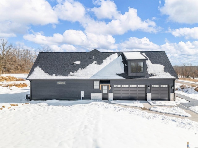 snow covered back of property featuring a garage