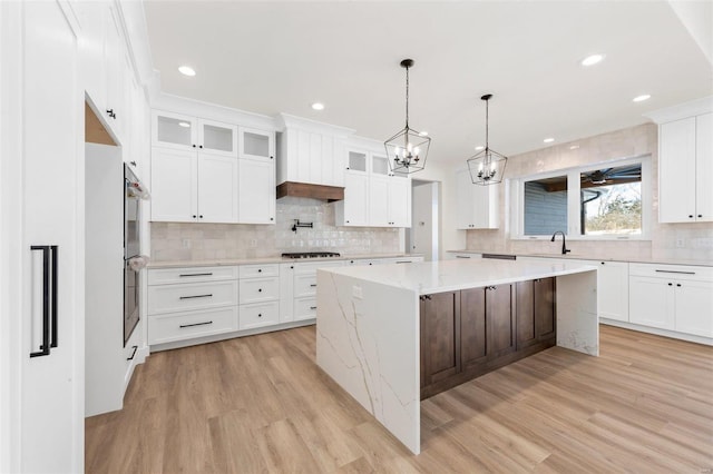 kitchen featuring sink, white cabinets, light hardwood / wood-style floors, gas stovetop, and a kitchen island