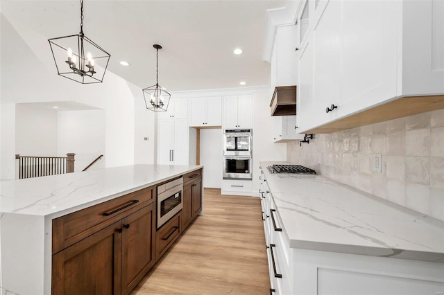 kitchen featuring white cabinets, stainless steel appliances, decorative light fixtures, and tasteful backsplash