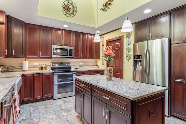 kitchen with light stone counters, hanging light fixtures, decorative backsplash, and appliances with stainless steel finishes