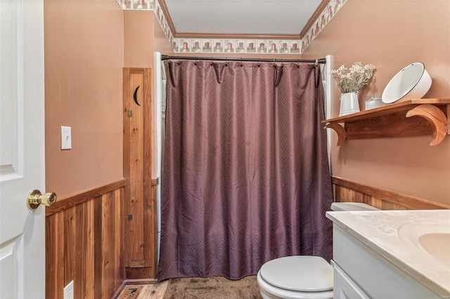 bathroom with vanity, wooden walls, ornamental molding, and toilet