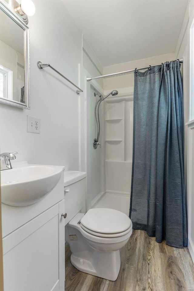 bathroom with wood-type flooring, toilet, curtained shower, and vanity