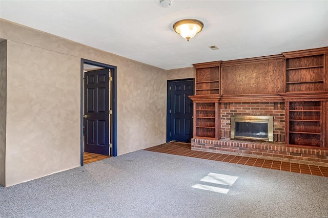 unfurnished living room with a brick fireplace, carpet, and built in shelves