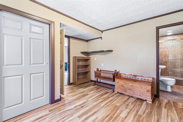 interior space featuring ornamental molding, light wood-type flooring, and ensuite bath