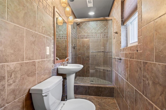 bathroom featuring tile walls, a shower with shower door, tile patterned floors, and toilet