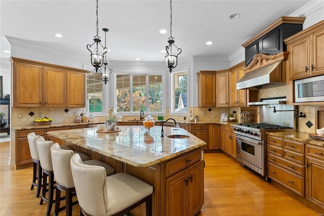 kitchen with appliances with stainless steel finishes, backsplash, a kitchen island with sink, sink, and pendant lighting