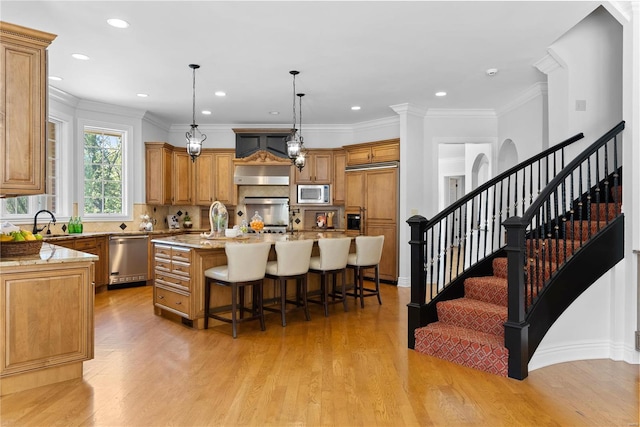 kitchen featuring light stone countertops, built in appliances, a breakfast bar area, and an island with sink