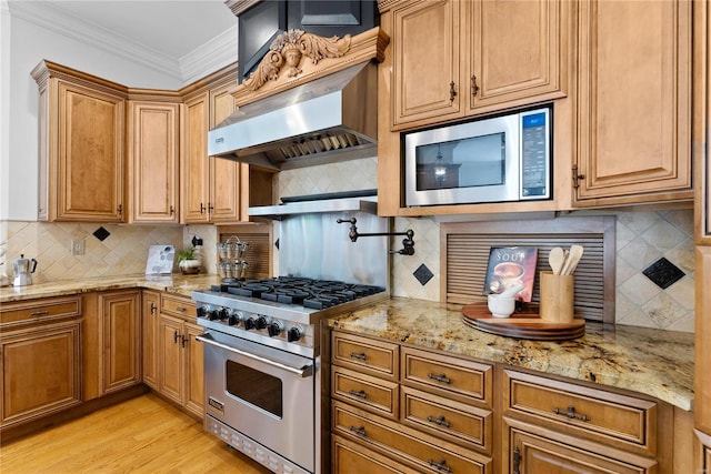 kitchen featuring light stone countertops, wall chimney exhaust hood, decorative backsplash, appliances with stainless steel finishes, and ornamental molding