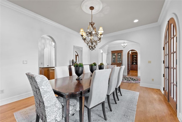 dining space featuring ornamental molding, light wood-type flooring, and a notable chandelier