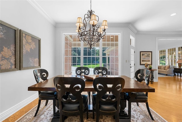 dining room featuring wood-type flooring, ornamental molding, and a notable chandelier